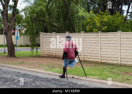 Johannesburg, Südafrika - Unbekannter körperlich behinderten Mann auf Krücken Kampf durch die Straßen der Stadt, Bild im Querformat Stockfoto