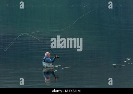 Fischer, Taille tief in sehr ruhigem Wasser, während Fliegen - Casting. Stockfoto