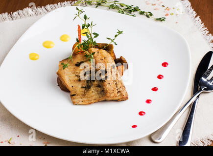 Gebackener Fisch mit Kartoffeln und Pilze auf eine weisse Platte Stockfoto