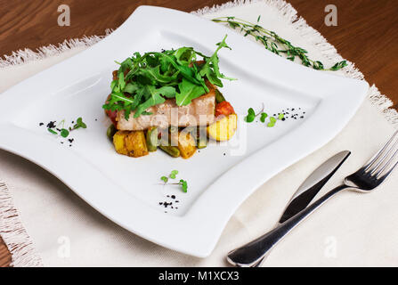 Gebackene Fischfilets mit Kartoffeln und grünen Bohnen auf eine quadratische Platte Stockfoto