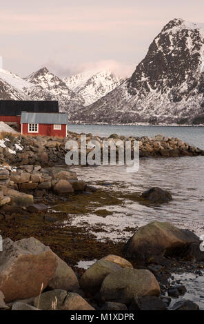 Eine rote Fischerhütte und schneebedeckten Landschaft, die von der E10 Flakstadøya auf den Lofoten in Norwegen Stockfoto