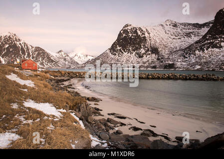 Eine rote Fischerhütte und schneebedeckten Landschaft, die von der E10 Flakstadøya auf den Lofoten in Norwegen Stockfoto