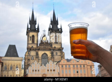 Nahaufnahme, Mann, Hand, wiederverwendbare Glas voller Bier über das Stadtbild mit Kathedrale Unserer Lieben Frau vor Tyn, Prag, Tschechische Republik Stockfoto