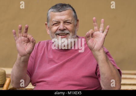 Schönes Portrait von bärtigen älteren Mann glücklich sein und zeigen, dass alles in Ordnung ist, Stockfoto