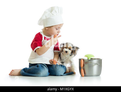 Cute kid Boy gekleidet Koch spielt mit lustigen Hunde isoliert Stockfoto