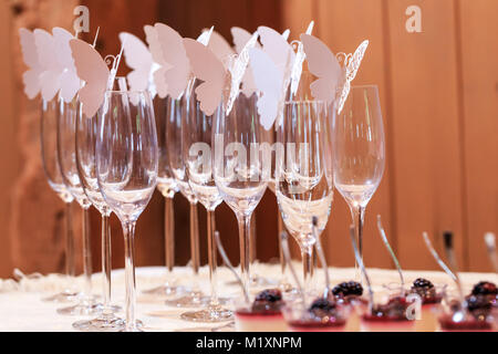 Gläser mit Papier Schmetterlinge auf Tabelle mit einer Zeremonie dekoriert. Dekoration aus Papier Schmetterlinge auf leere Gläser auf der Tafel. Stockfoto