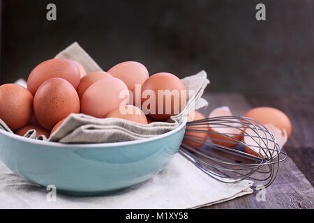 Braun Bauernhof frisches Huhn Eier von freilaufenden Hühnern mit Schneebesen über eine rustikale Holz- Hintergrund. Stockfoto