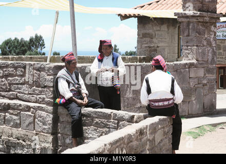 Drei Männer, die in traditionellen Outfits für die Insel Taquile Region angezogen, einer von ihnen Stricken ein Hut. Der Titicacasee, Peru - 17. Oktober 2012 Stockfoto