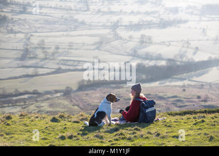 Großbritannien, Derbyshire, ein Walker und ihr Hund, bewundern Sie die Aussicht auf Hoffnung Tal von Mam Tor. Stockfoto