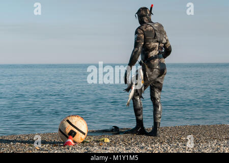 Scuba Diver erwachsener Mann auf einer Küste mit frisch gefangene Fische und Unterwasserjagd Gang (Flossen, speargun) Stockfoto