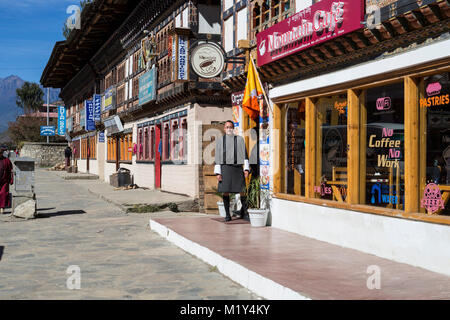 Paro, Bhutan. Speichert auf der Paro Hauptstraße. Mann, der traditionelle männliche Kleid, ein Gho. Stockfoto