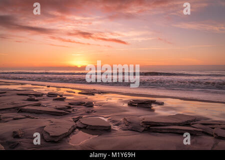 Sonnenaufgang über dem Atlantik auf einem gefrorenen Robert Moses Strand Stockfoto