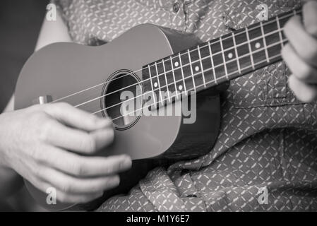 In der Nähe von Mädchen Hand strumming Sopran Ukulele monochromen Bild Stockfoto