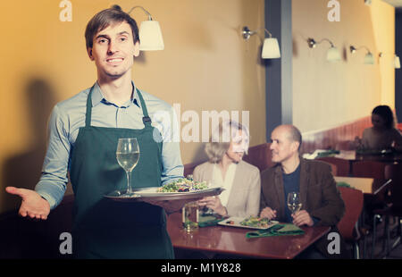 Portrait von Kellner in normalen Restaurant arbeiten und halten Fach Stockfoto