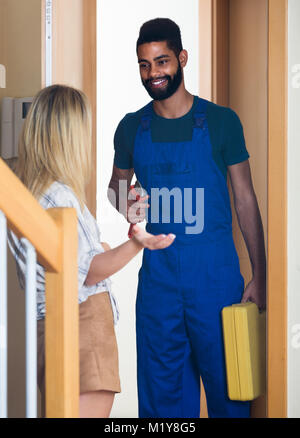 Fröhliche amerikanische Hausfrau meeting professional Arbeiter mit Werkzeugen zur Tür Stockfoto