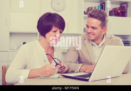 Lächelnde Mutter und Sohn neue Software auf dem Laptop am Tisch sitzen berücksichtigen Stockfoto
