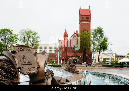 Minsk, Weißrussland - Mai 18, 2017: Brunnen auf dem Platz der Unabhängigkeit in Minsk auf dem Hintergrund der roten Kathedrale von St. Simon und Helena von der Kath. Stockfoto