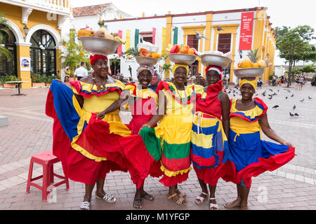 Cartagena, Kolumbien - Januar 23th, 2018: Fünf palenqueras mit einem Metall Korb mit Früchten stellen Ihre multicolor traditionelles Kleid an. Stockfoto