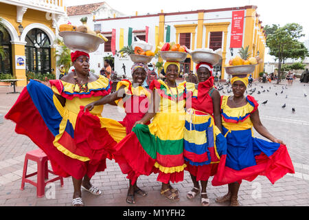 Cartagena, Kolumbien - Januar 23th, 2018: Fünf palenqueras mit einem Metall Korb mit Früchten stellen Ihre multicolor traditionelles Kleid an. Stockfoto