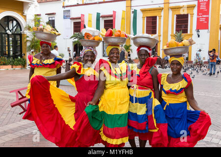 Cartagena, Kolumbien - Januar 23th, 2018: Fünf palenqueras mit einem Metall Korb mit Früchten stellen Ihre multicolor traditionelles Kleid an. Stockfoto