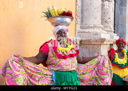 Cartagena, Kolumbien - Januar 23th, 2018: eine Frau mit einem palenquera Metall Korb mit Früchten posiert sie Cognac traditionelle Kleidung an der ol angezeigt Stockfoto