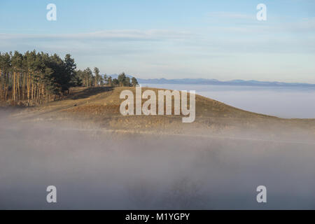 Ein kleiner Hügel steigende oberhalb der dichten Nebel an einem sonnigen Nachmittag in den Ausläufern der Karpaten. Stockfoto