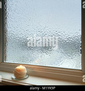 Kerze in der Nähe von Milchglas Fenster. Wetter nach dem Regen. Stockfoto