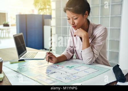 Junge asiatische Gebäude Designer allein sitzen an einem Tisch in einem modernen Büro in Gebäude designs konzentrieren Stockfoto