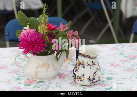 Teekanne voller Frühlingsblumen auf einem Tisch Stockfoto