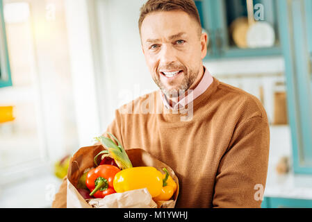 Nette Mann hält einen Beutel mit Lebensmitteln begeistert Stockfoto