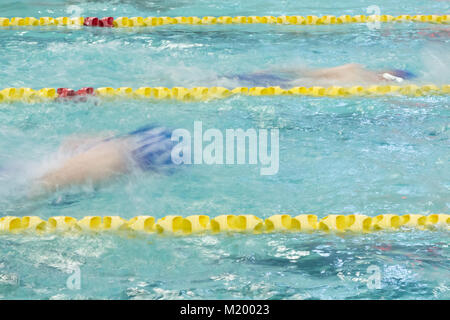 Schwimmer konkurrieren in einem Bad im Innenpool. Bewegungsunschärfe zeigt Ihre Bewegung, als sie durch das Wasser fahren. Stockfoto