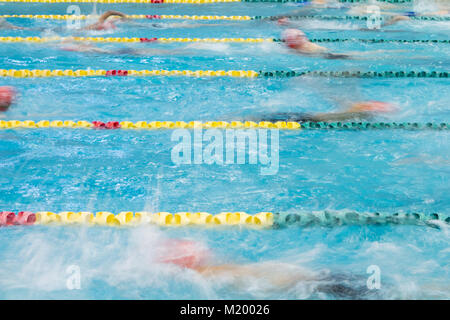 Schwimmer warmup in einem Hallenbad zu schwimmen. Bewegungsunschärfe zeigt Ihre Bewegung, als sie durch das Wasser fahren. Stockfoto