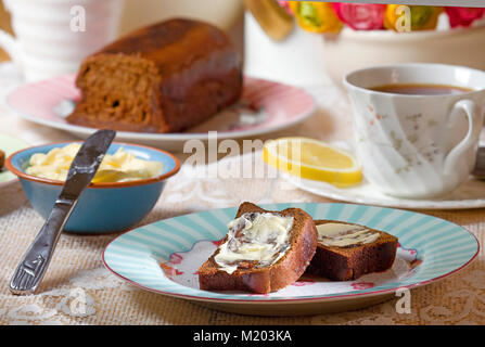 Tabelle Einstellung mit in Scheiben geschnittenen Malz Brot mit Butter und schwarzer Tee mit Zitrone Stockfoto