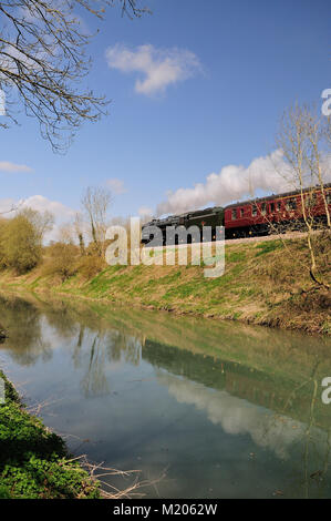 Das stille Wasser des Kennet & Avon Kanals spiegelt BR Standard No. 70013 'Oliver Cromwell' wider, als es mit seinem Support-Trainer nach Westen fährt, 4.. April 2009. Stockfoto