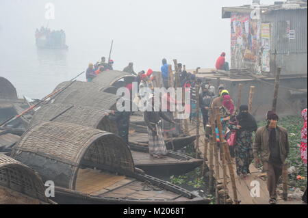 Boot Männer fahren Ihr Boot mit Passagieren auf einem kalten und nebligen Winter morgen auf der Shitalokha Fluss in Naraynganj, Bangladesch Stockfoto