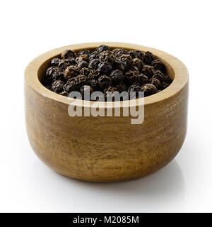 Ganze schwarze Pfefferkörner in dunklem Holz Schüssel isoliert auf Weiss. Stockfoto