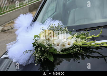 Die Haube ein schwarzes Auto ist mit einem Blumenstrauß in eine Hochzeit-Stil dekoriert. Stockfoto