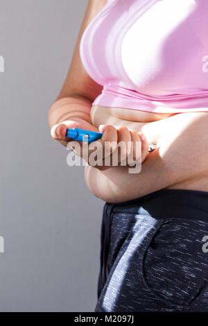 MODEL RELEASED. Frau Injektion selbst in den Bauch. Stockfoto