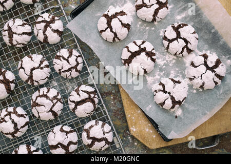 Hausgemachte Schokolade Crinkle Cookies auf ein Backblech und Kühlung Rack auf schiefer Hintergrund Stockfoto