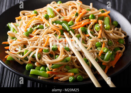 Japanisches Essen: Soba mit Karotten, Erbsen und grüne Bohnen close-up auf einem Teller. Horizontale Stockfoto