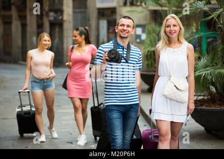 Portrait von glückliches Paar Touristen, die zu Fuß und ziehen Gepäcktaschen zusammen Stockfoto