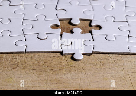 Weiß Stichsäge/Puzzle mit einem Stück an der falschen Position, über schwarzen Holztisch Hintergrund, Symbol der Problemlösung und neue Vision Stockfoto