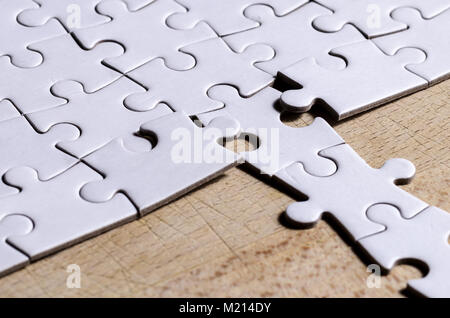 Weiß Stichsäge/Puzzle mit einer Zeile in falscher Position, über holztisch Hintergrund, Symbol der Problemlösung und neue Vision Stockfoto