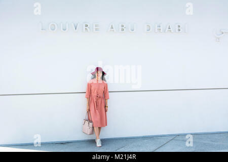 ABU DHABI, VEREINIGTE ARABISCHE EMIRATE - Januar 26, 2018: Happy asiatische Tourist im Louvre Abu Dhabi Eingang Stockfoto