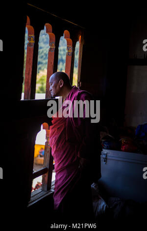 Prakhar Lhakhang, Bumthang, Bhutan. Buddhistischer Mönch Beobachten religiösen Tanz aus einem Fenster im Kloster. Stockfoto