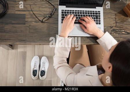 Erhöhte Auffassung vom Sport Schuhe neben der Unternehmerin mit Laptop im Büro Stockfoto