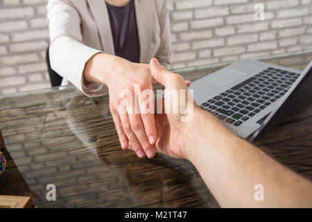 Nahaufnahme einer Geschäftsfrau Händeschütteln mit Ihrem Partner über den Schreibtisch im Büro Stockfoto