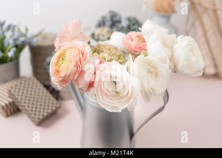 Persische buttercup. Bündel bunten Ranunkeln Blumen hellen Hintergrund. Metall Vase auf pink vintage Holztisch. Stockfoto