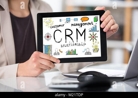 Geschäftsfrau, die Customer Relationship Management Konzept, das auf digitalen Tablet am Arbeitsplatz Stockfoto