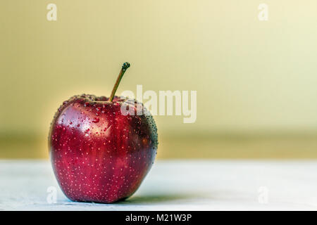 Lecker roter Apfel mit Wassertropfen auf grünem Hintergrund Stockfoto